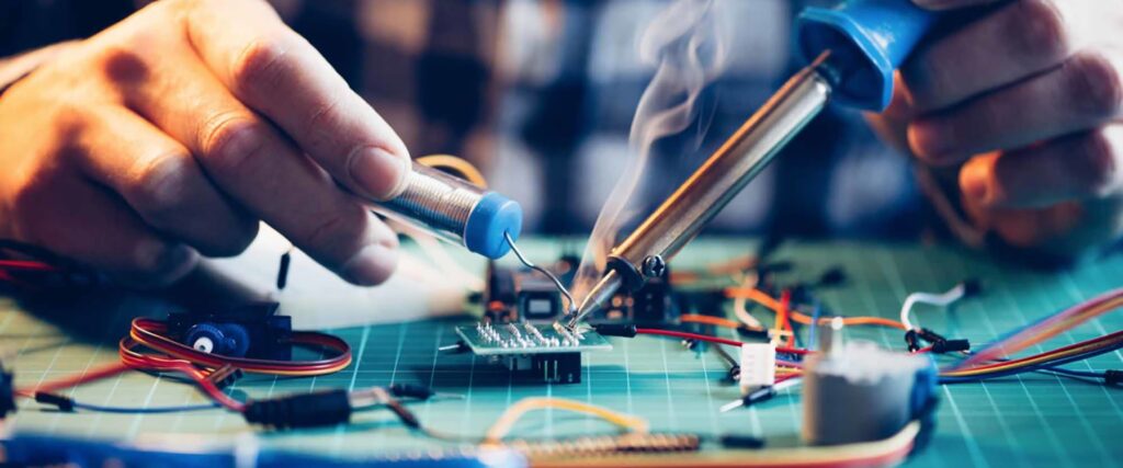 Technician soldering components on an electronics repair bench