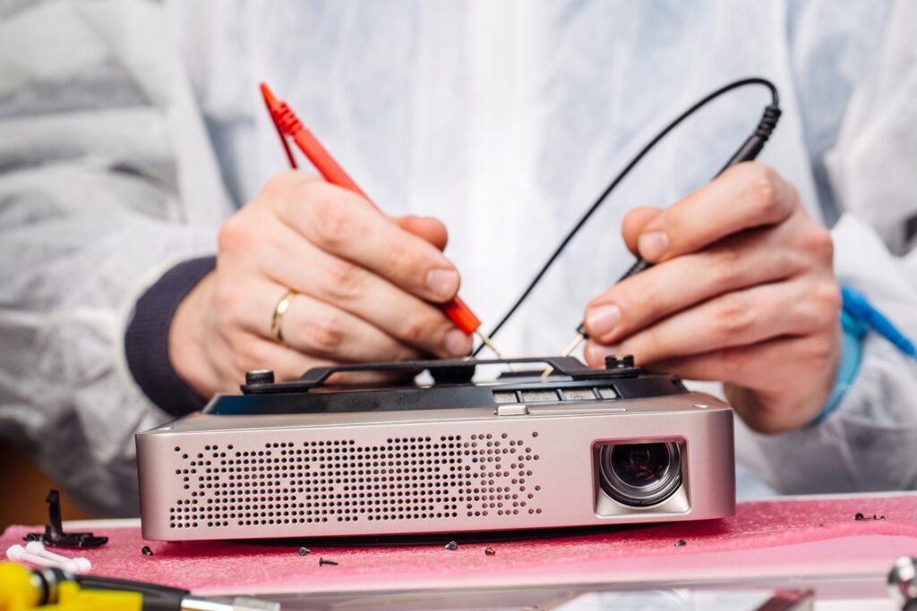 Technician testing a projector with multimeter probes